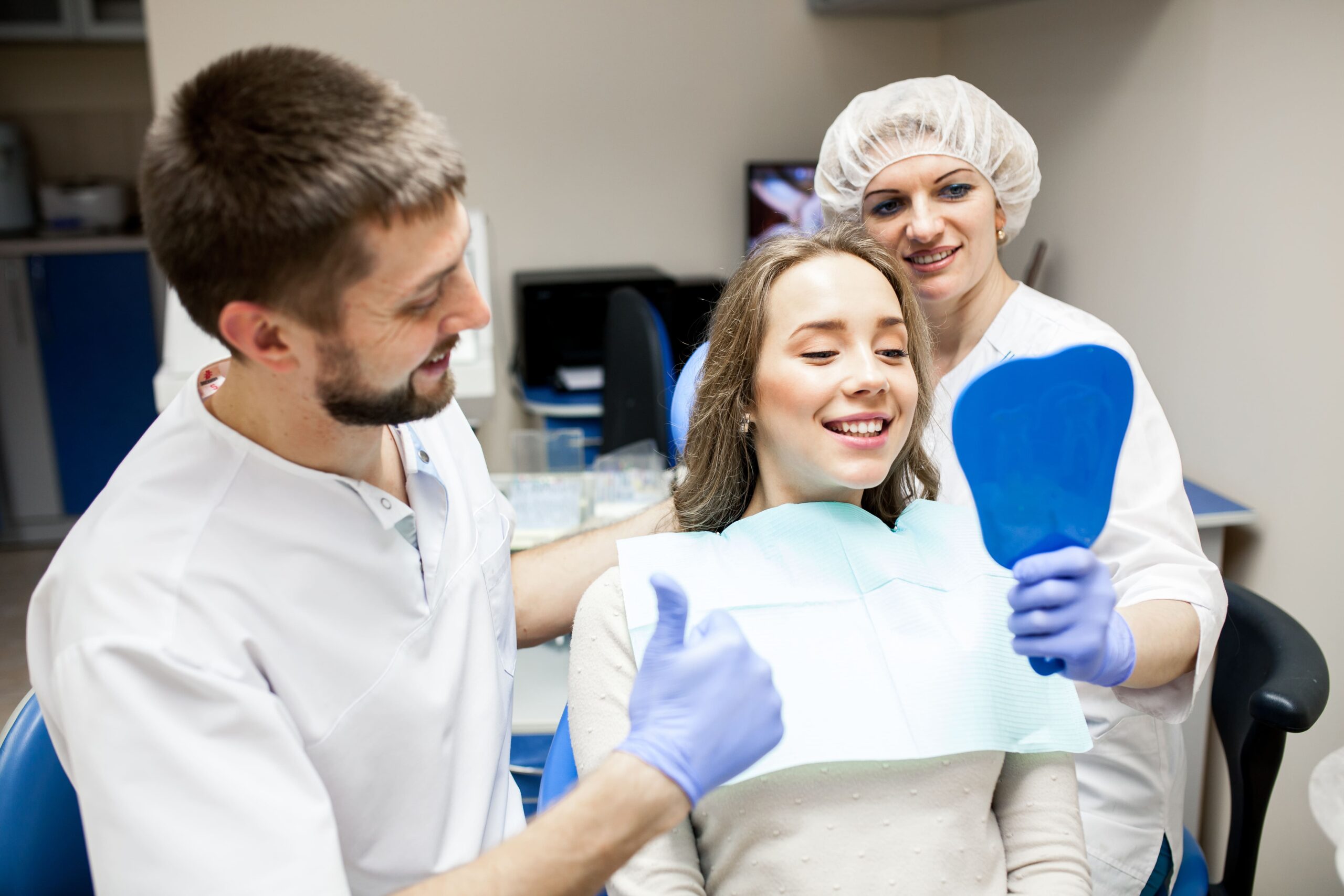 Happy patient with a mirror and dental team at an advanced Periodontics and Implant Dentistry clinic in Holmdel, NJ.